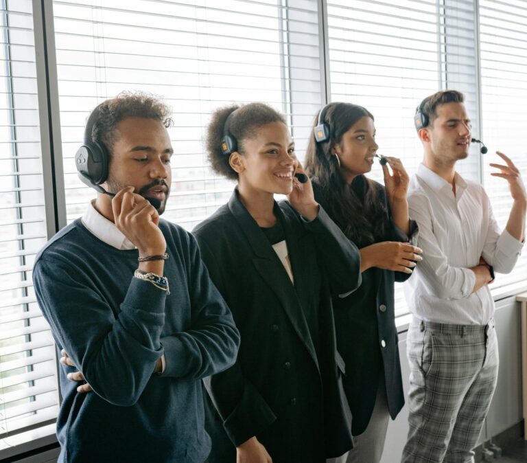 Diverse call center team collaborating in a modern office, wearing headsets and smiling.